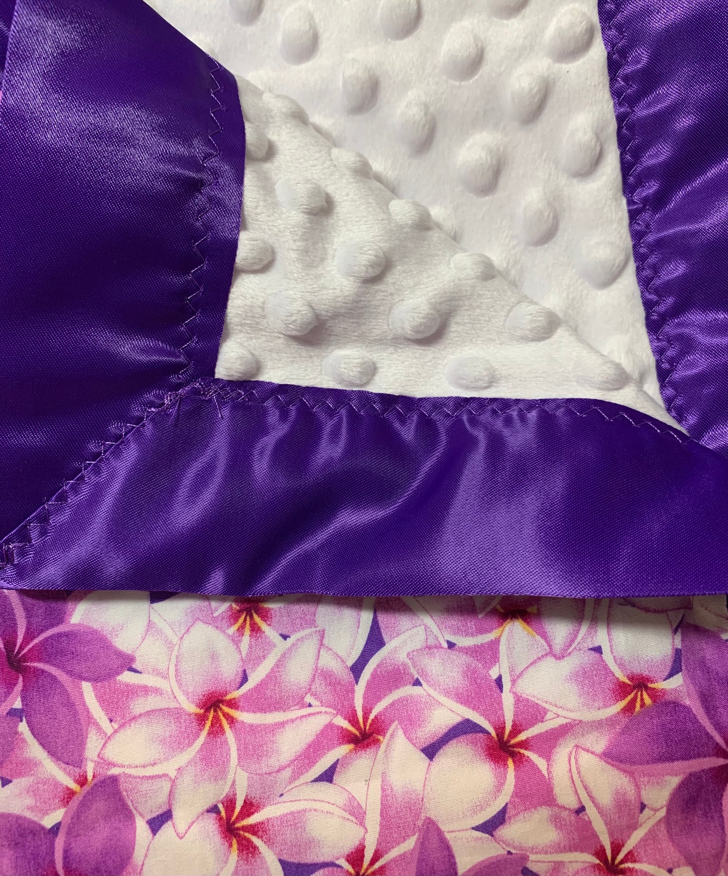 100% Cotton plumeria print with white Minky and satin trim baby blanket